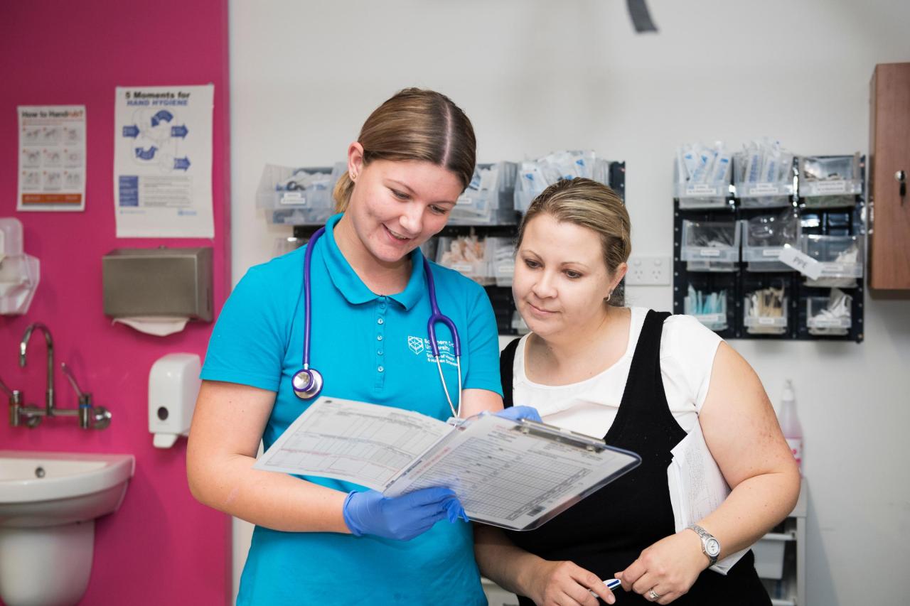 Woman in scrubs and other woman looking at document