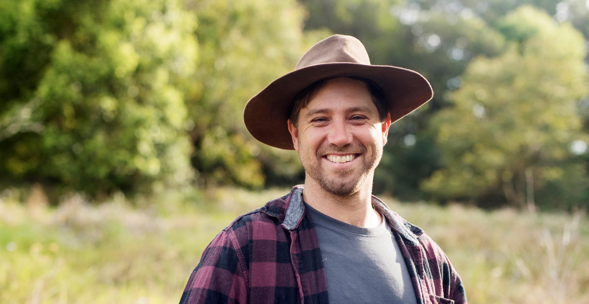 Man wearing hat smiling in a paddock